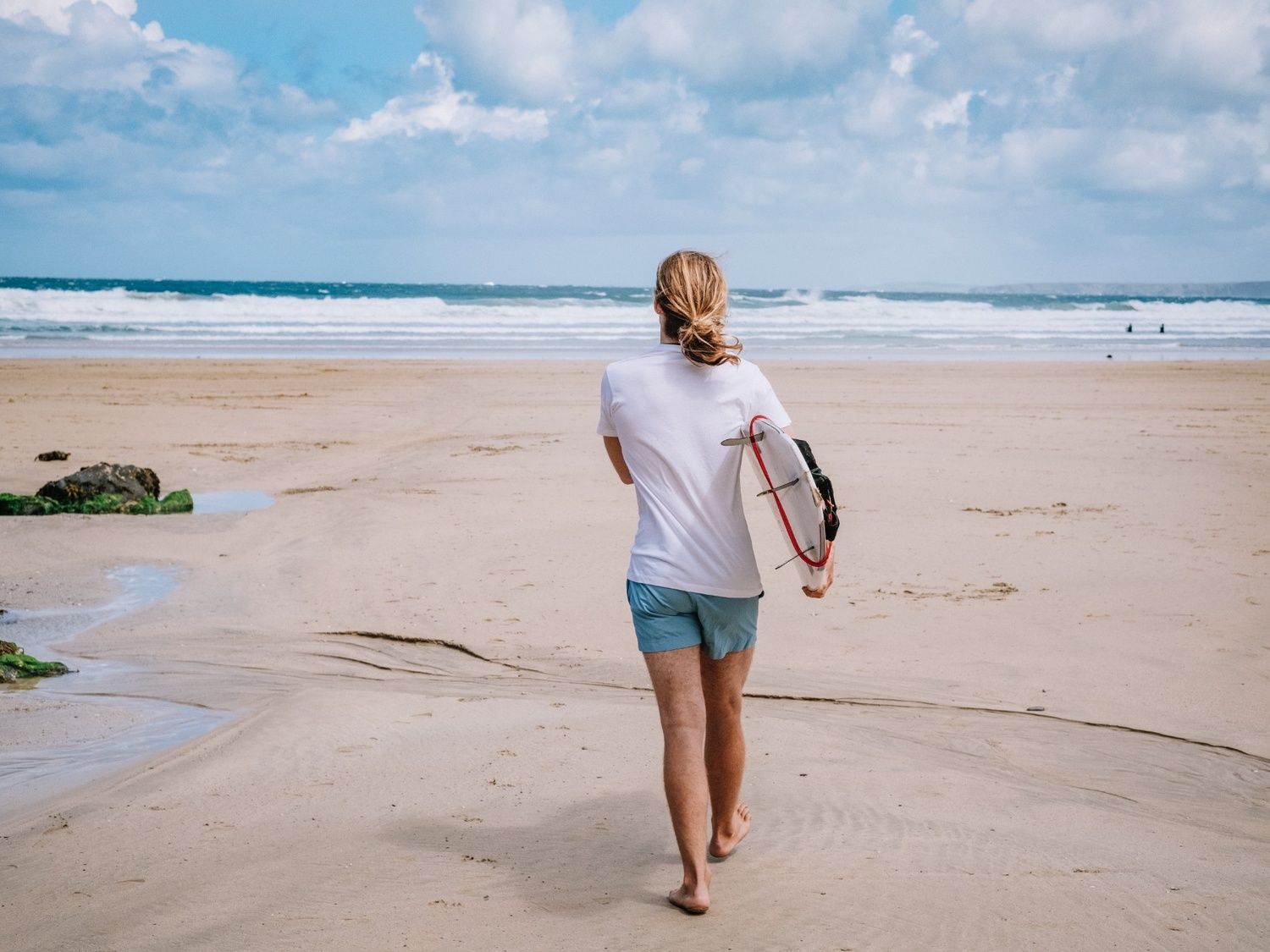 A surfer walking towards the sea